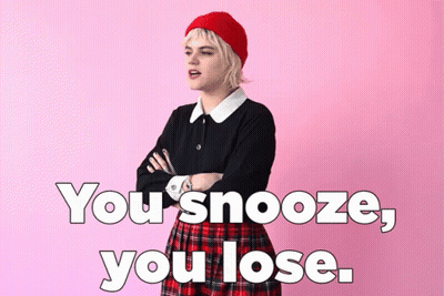A Woman In A Plaid Skirt Is Standing With Her Arms Crossed In Front Of A Pink Background With The Words You Snooze You L GIF