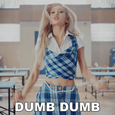 A Woman In A Plaid Top And Skirt Is Standing In Front Of A Sign That Says " Dumb Dumb " GIF