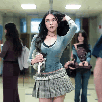 A Woman In A Pleated Skirt Holds Her Hair In A Hallway GIF