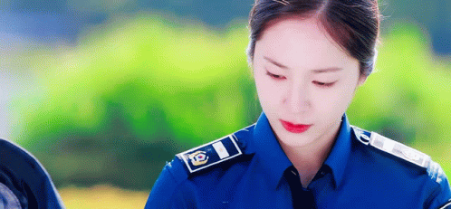 A Woman In A Police Uniform Is Looking Down GIF
