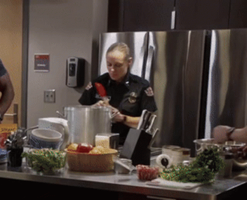 A Woman In A Police Uniform Is Preparing Food GIF
