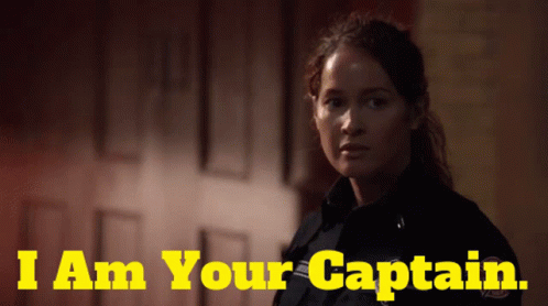 A Woman In A Police Uniform With The Words I Am Your Captain Behind Her GIF