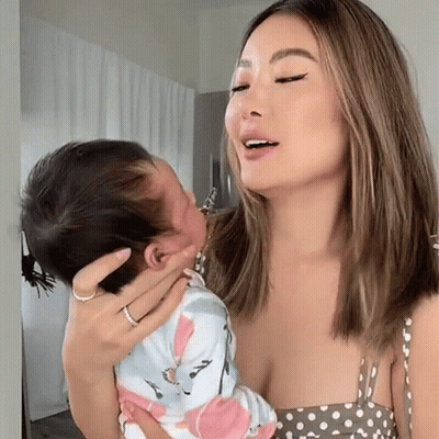 A Woman In A Polka Dot Dress Holds A Baby GIF
