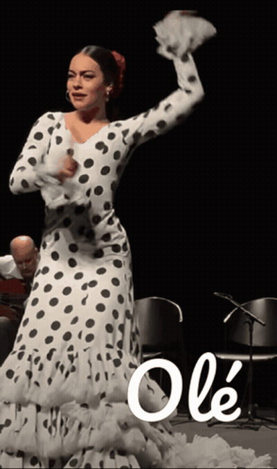 A Woman In A Polka Dot Dress Is Dancing In Front Of A Man Playing Guitar GIF