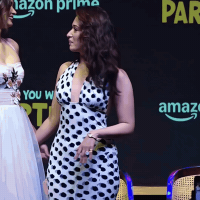 A Woman In A Polka Dot Dress Stands Next To Another Woman In A White Dress GIF