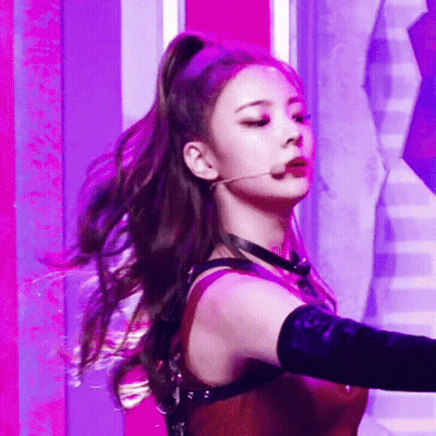 A Woman In A Ponytail Is Singing Into A Microphone While Wearing A Choker . GIF