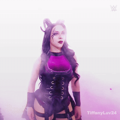 A Woman In A Purple And Black Costume With Horns Is Standing In A Room With Smoke Coming Out Of It . GIF