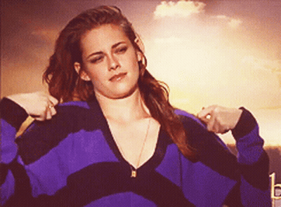 A Woman In A Purple And Black Striped Sweater Is Adjusting Her Sweater GIF