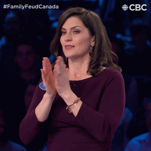 A Woman In A Purple Dress Is Applauding In Front Of A Crowd And The Words Family Feud Canada Are Above Her GIF