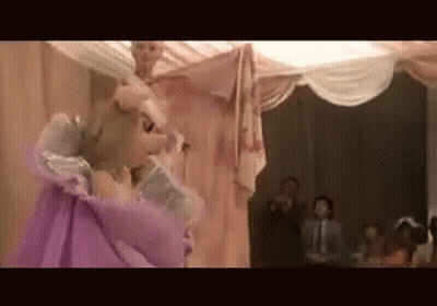 A Woman In A Purple Dress Is Dancing On A Stage In Front Of A Crowd GIF