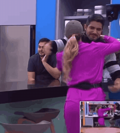 A Woman In A Purple Dress Is Dancing With A Man In A Kitchen . GIF