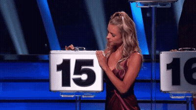 A Woman In A Purple Dress Is Holding A Briefcase With The Number 15 On It GIF