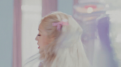 A Woman In A Purple Dress Is Looking At Her Reflection In A Mirror GIF