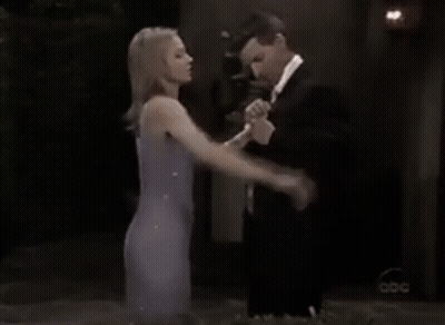 A Woman In A Purple Dress Is Shaking Hands With A Man In A Suit And Bow Tie GIF