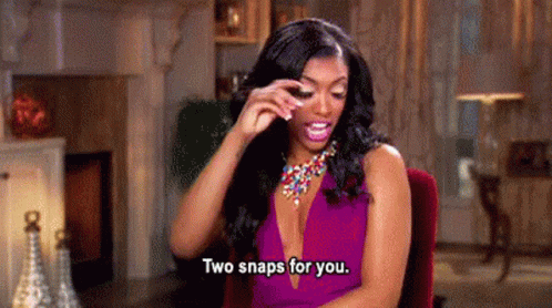 A Woman In A Purple Dress Is Sitting In A Chair In A Living Room . GIF