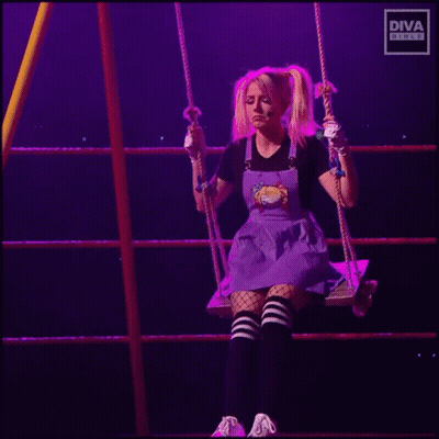 A Woman In A Purple Dress Is Sitting On A Swing In A Ring . GIF