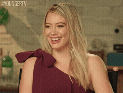 A Woman In A Purple Dress Is Smiling And Sitting In A Chair With #Youngertv Written Above Her GIF