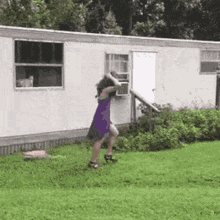 A Woman In A Purple Dress Is Standing In Front Of A White Trailer . GIF