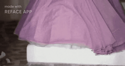A Woman In A Purple Dress Is Standing On A White Block Of Ice . GIF