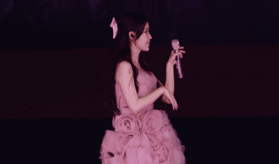 A Woman In A Purple Dress Sings Into A Microphone GIF