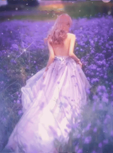 A Woman In A Purple Dress Walking Through A Field Of Purple Flowers GIF