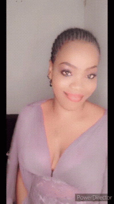 A Woman In A Purple Dress With A Plunging Neckline Is Smiling GIF