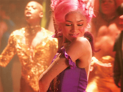A Woman In A Purple Dress With Pink Hair Is Smiling GIF
