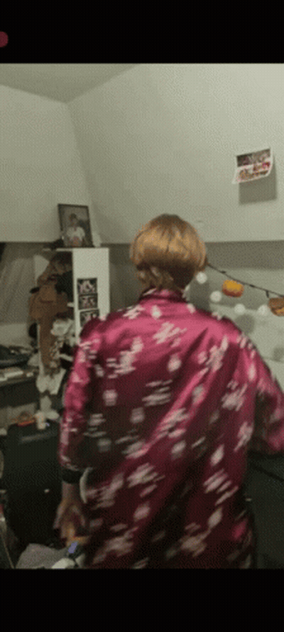 A Woman In A Purple Floral Shirt Is Standing In A Room GIF