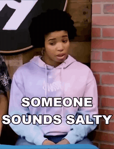 A Woman In A Purple Hoodie Is Sitting In Front Of A Brick Wall And Someone Sounds Salty GIF