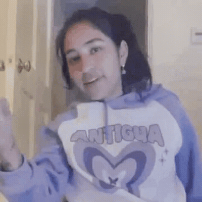 A Woman In A Purple Hoodie Is Smiling And Holding A Knife In Her Hand . GIF