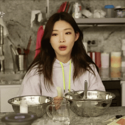 A Woman In A Purple Hoodie Sits At A Counter With Bowls Of Food And A Glass Of Water GIF
