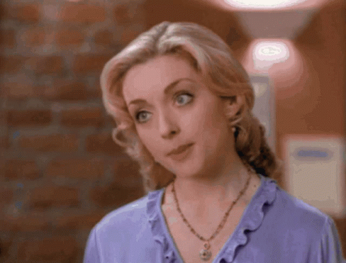 A Woman In A Purple Jacket And A Blue Shirt Looks Surprised GIF
