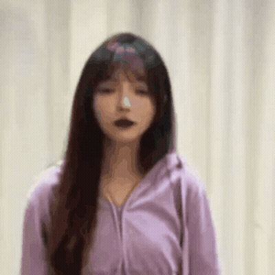 A Woman In A Purple Jacket Is Standing In Front Of A White Curtain . GIF