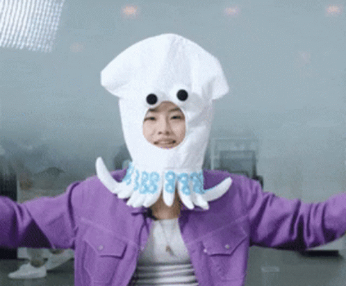 A Woman In A Purple Jacket Is Wearing A White Squid Costume GIF