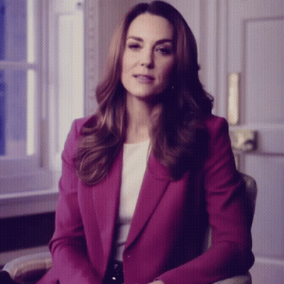 A Woman In A Purple Jacket Sits In A Chair GIF