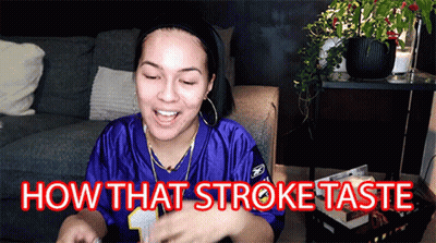 A Woman In A Purple Jersey Is Sitting On A Couch And Says How That Stroke Taste GIF