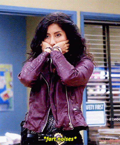A Woman In A Purple Leather Jacket Is Covering Her Mouth With Her Hands And The Word Fart Noises Is On Her Belt GIF