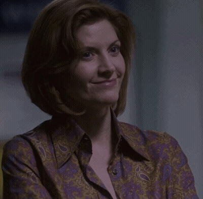 A Woman In A Purple Paisley Shirt Is Smiling GIF