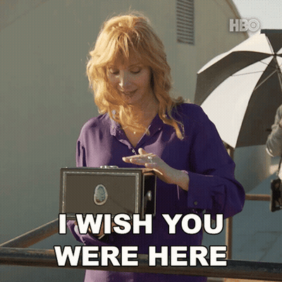 A Woman In A Purple Shirt Holds A Box And Says I Wish You Were Here GIF