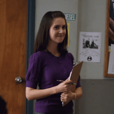A Woman In A Purple Shirt Is Holding A Clipboard In Front Of A Political Club Poster GIF