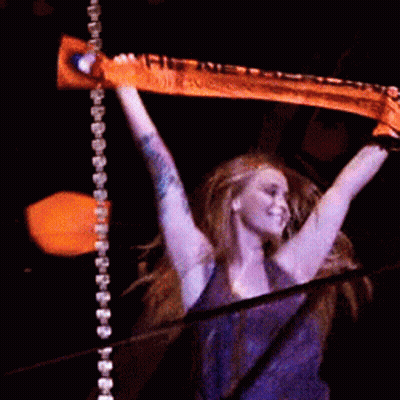 A Woman In A Purple Shirt Is Holding A Scarf In Her Hands GIF