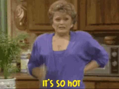 A Woman In A Purple Shirt Is Holding A Spray Bottle And Says It 'S So Hot . GIF