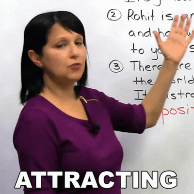 A Woman In A Purple Shirt Is Pointing At A Whiteboard With The Word Attracting On It GIF