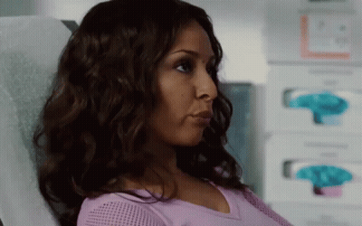 A Woman In A Purple Shirt Is Sitting In A Hospital Bed . GIF