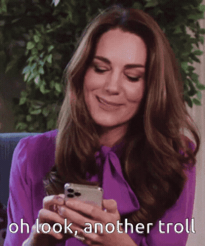 A Woman In A Purple Shirt Is Smiling While Looking At Her Phone GIF
