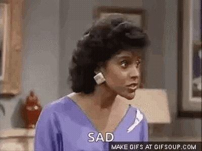 A Woman In A Purple Shirt Is Standing In A Living Room And Saying `` Sad '' . GIF