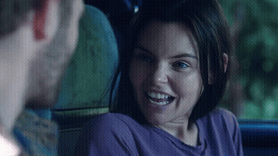 A Woman In A Purple Shirt Smiles While Looking At A Man GIF