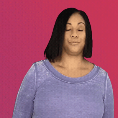A Woman In A Purple Shirt With Her Hair Blowing In The Wind Against A Pink Background GIF