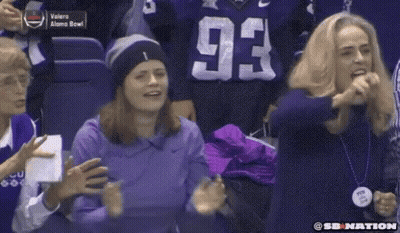 A Woman In A Purple Shirt With The Number 93 On It Stands In A Crowd Of People . GIF