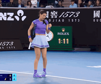A Woman In A Purple Skirt Stands On A Tennis Court With A Rolex Sign In The Background GIF